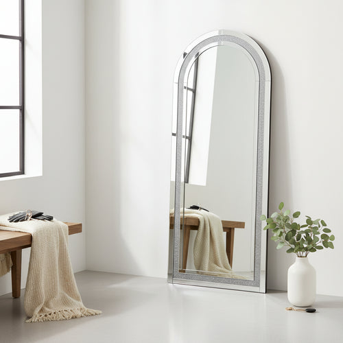 Modern arched floor mirror with textured frame in minimalist room beside wooden bench and plant
