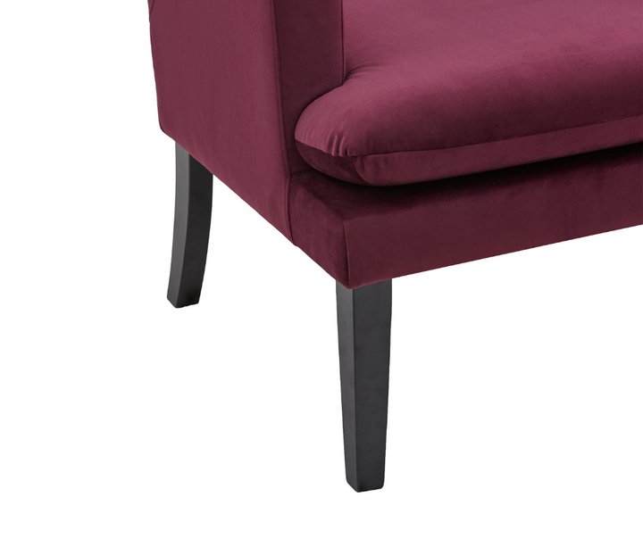 Burgundy velvet upholstered chair corner with black wooden legs