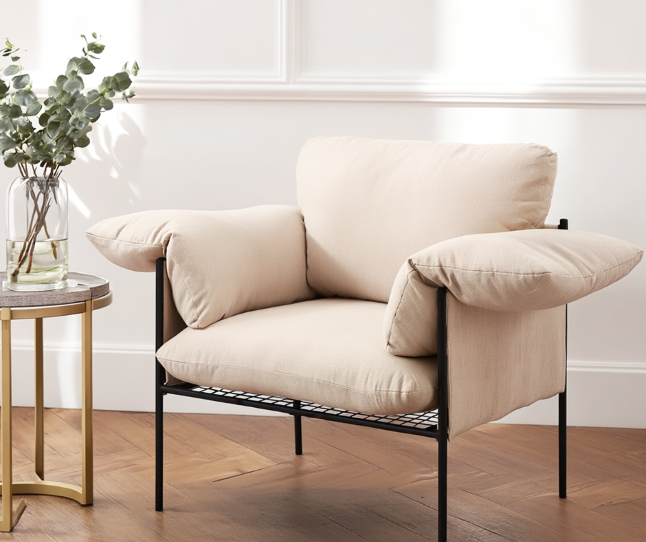 Modern beige accent armchair with plush cushions and black metal frame beside a round side table