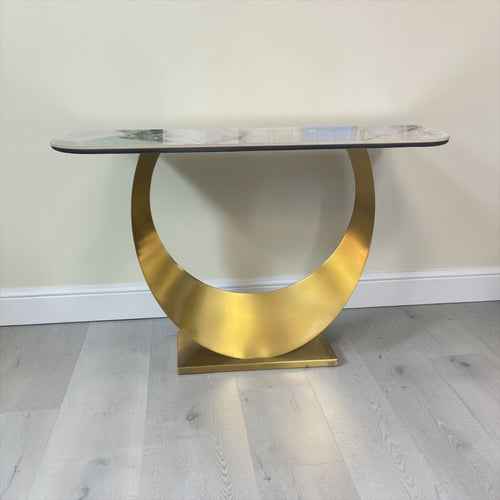 Modern console table with gold circular base and marble top on light wood floor