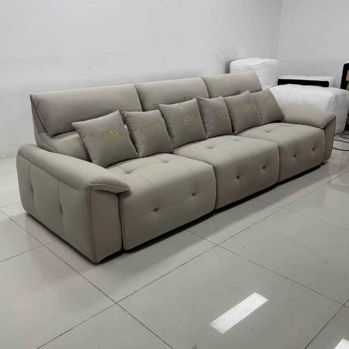 Modern beige sectional sofa with tufted seats and embroidered accent pillows in a minimalist room