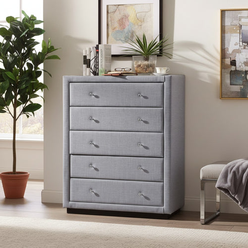Modern grey upholstered dresser with five drawers in a bright bedroom setting