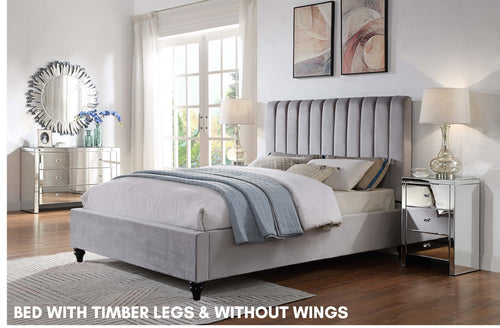 Modern gray upholstered bed with timber legs in bright bedroom, mirrored furniture