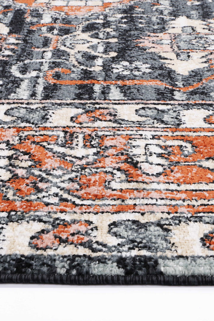 Close-up of a colorful area rug with black, orange, and cream geometric patterns.