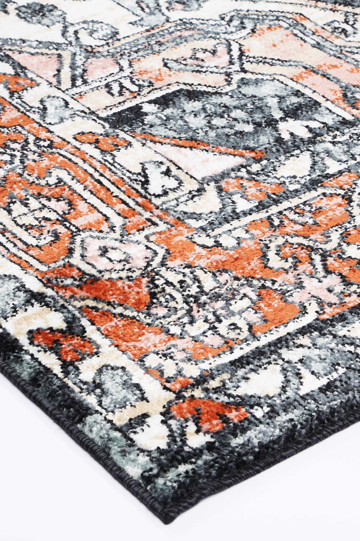 Close-up of modern area rug with abstract orange, grey, and cream geometric pattern