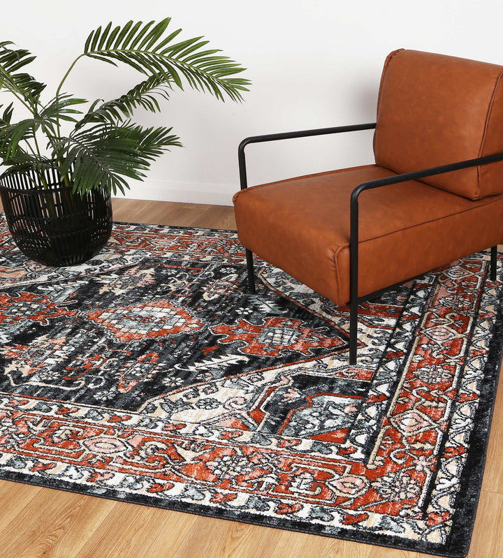 Modern living room with an orange accent chair, patterned area rug, and potted plant