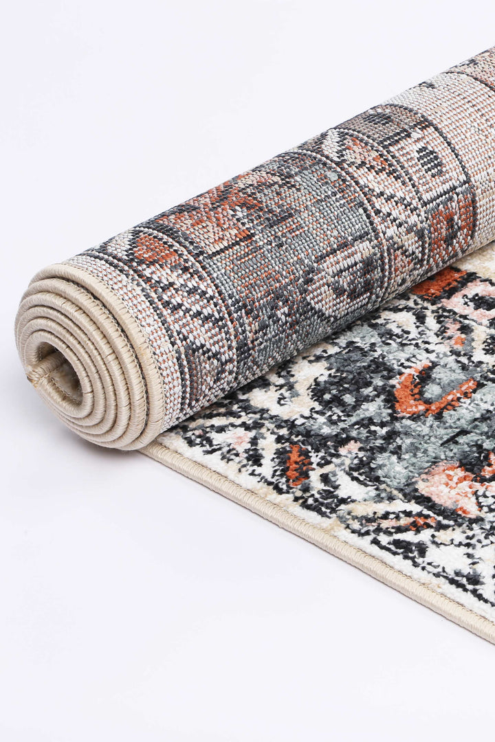 Rolled beige and multicolor area rug with geometric and floral pattern on a white background