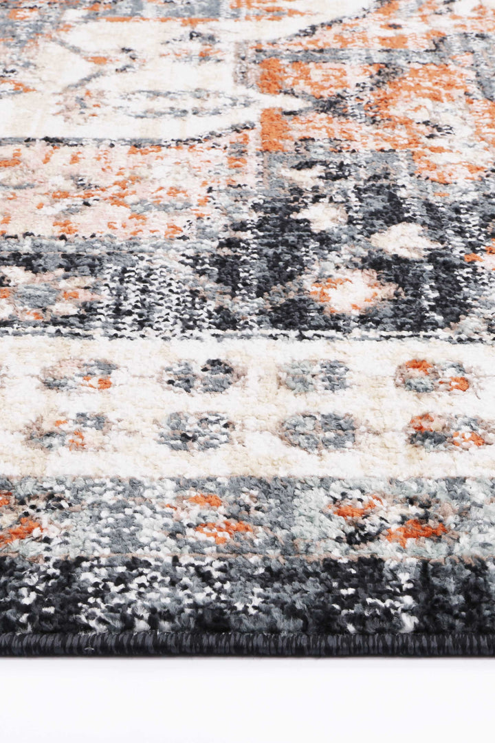 Close-up of textured area rug with abstract orange, black, grey, and cream pattern