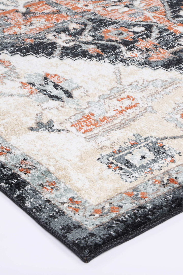 Corner of a modern area rug with beige, orange, and gray geometric pattern on a white background
