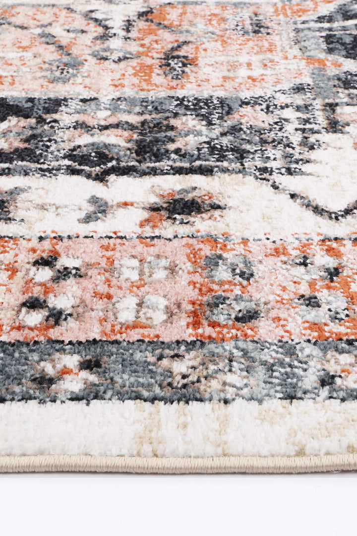 Close-up of multicolor area rug with orange, cream, blue, and gray geometric patterns