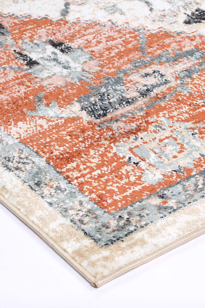 Close-up of a modern area rug with orange, gray, and cream geometric pattern on the corner