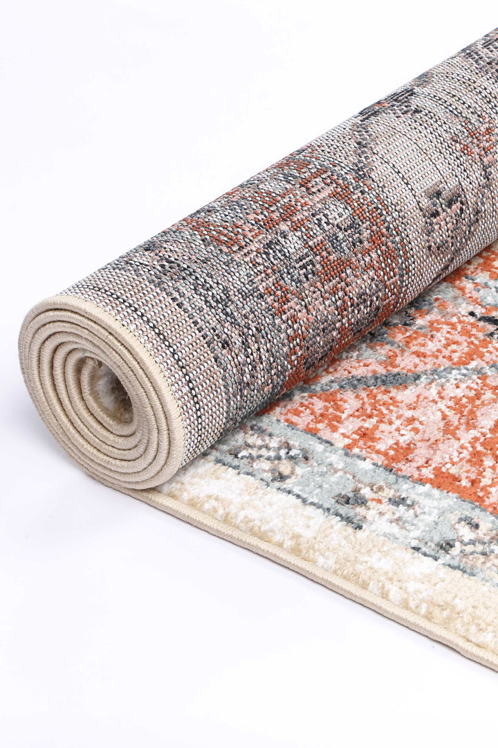 Rolled area rug with textured beige, orange, and gray pattern on white background