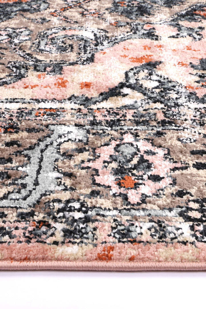 Close-up of beige and pink area rug with floral and abstract patterns, suitable for living room or bedroom decor.