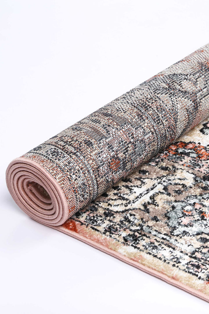 Rolled beige and multicolor area rug with traditional pattern on white background