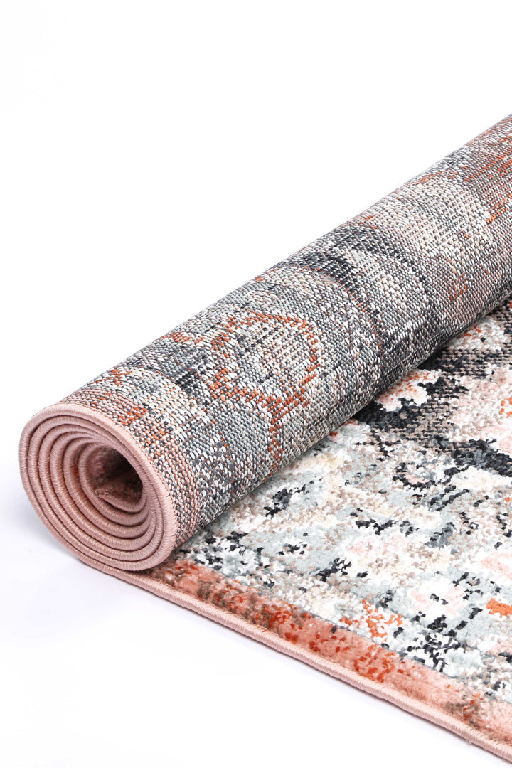 Rolled modern area rug with abstract beige, grey, and orange pattern on white background