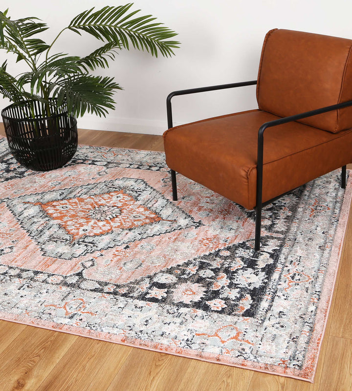 Modern living room with tan armchair, patterned area rug, and potted green plant on wood floor