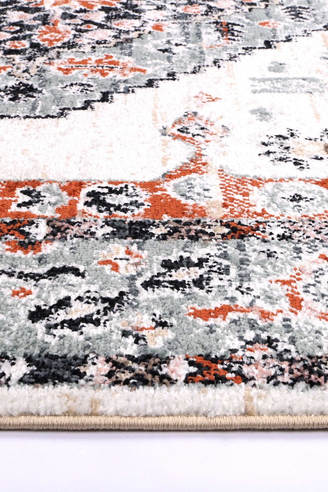 Close-up of a plush area rug with orange, grey, black, and white abstract pattern.
