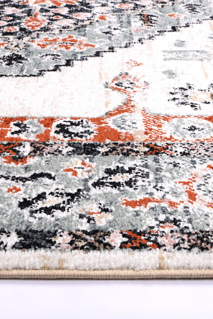 Close-up of a plush area rug with orange, grey, black, and white abstract pattern.