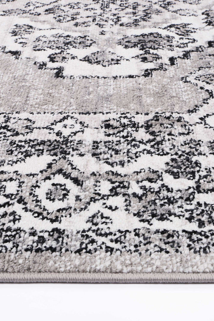 Close-up of a grey and white area rug with modern textured pattern and black accents
