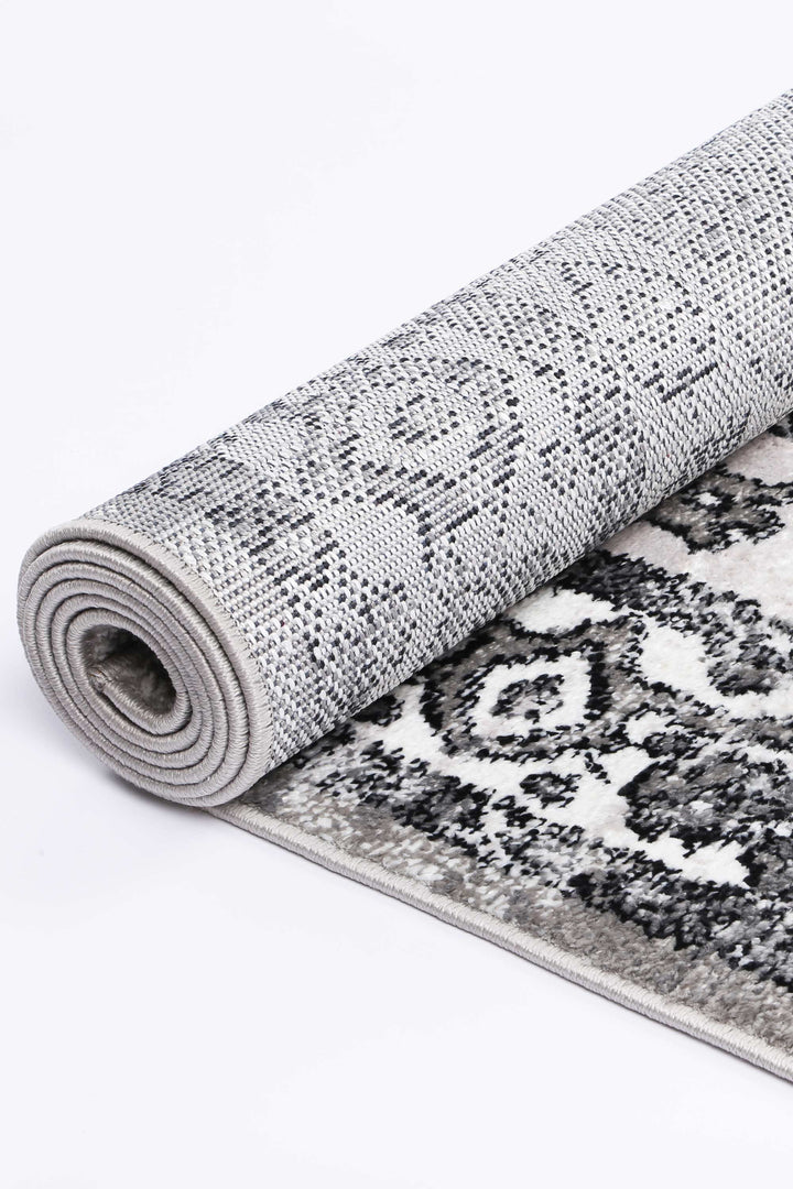 Rolled grey and black patterned area rug with soft texture on white background
