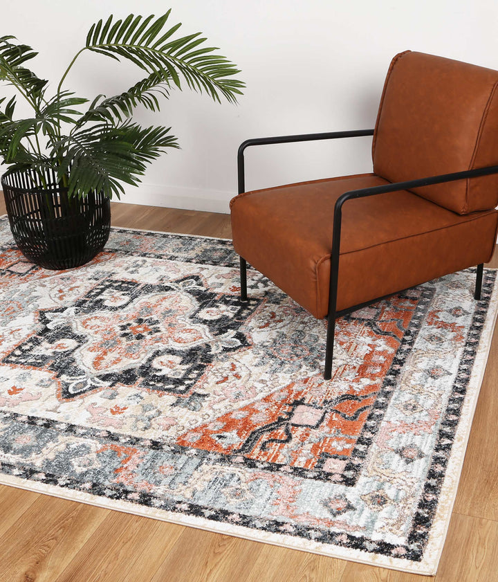 Modern living room with brown accent chair, patterned area rug, and potted green plant