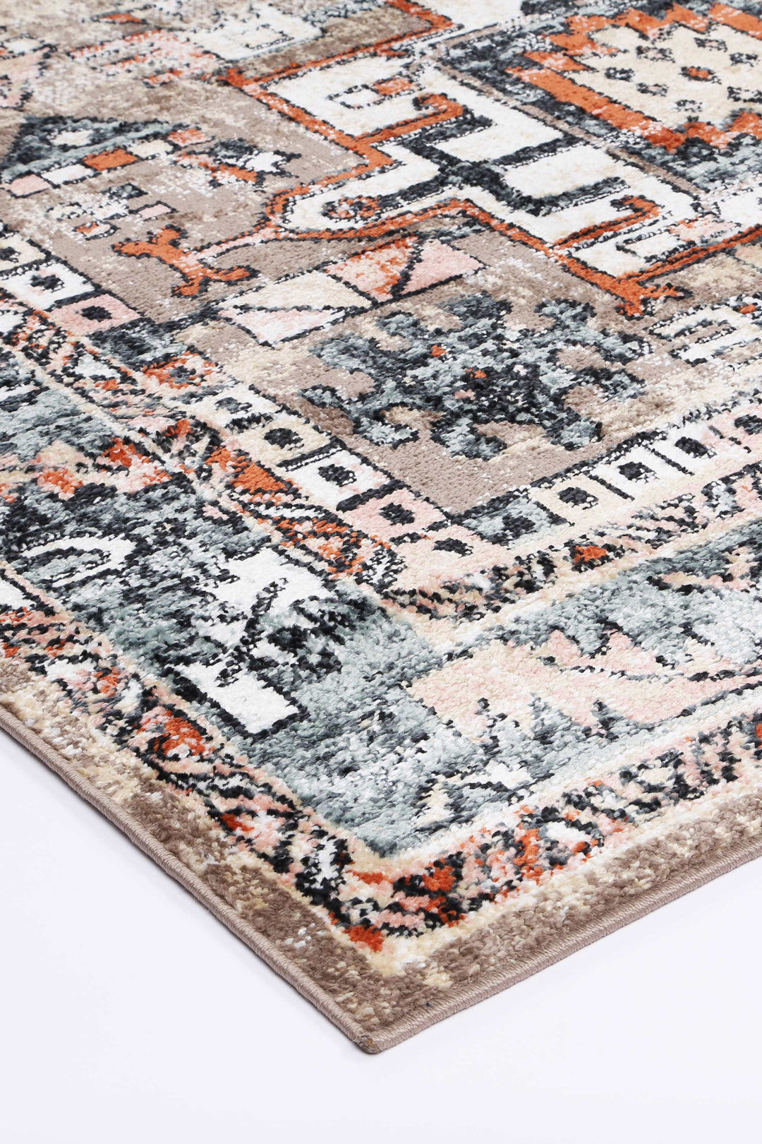 Detailed corner of a beige and orange geometric patterned area rug on a white floor