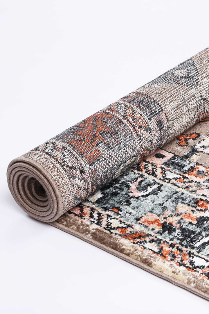 Rolled-up beige and multicolor area rug with geometric pattern, home decor accent
