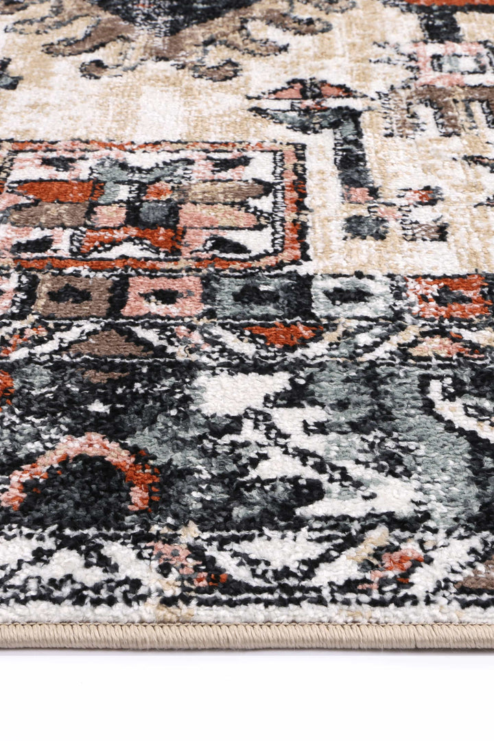 Close up of patterned area rug with beige, black, rust, and grey geometric designs