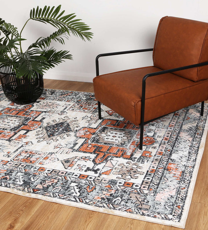 Modern brown armchair on patterned area rug with indoor plant in living room setting
