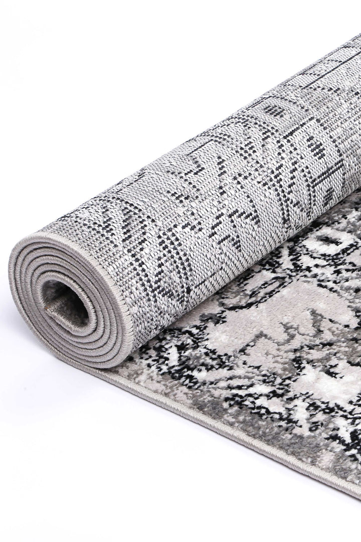 Rolled grey area rug with textured abstract pattern, soft pile, and detailed weave