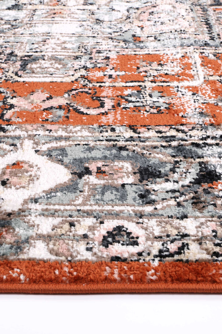 Close-up of a plush patterned area rug with orange, gray, and cream geometric designs