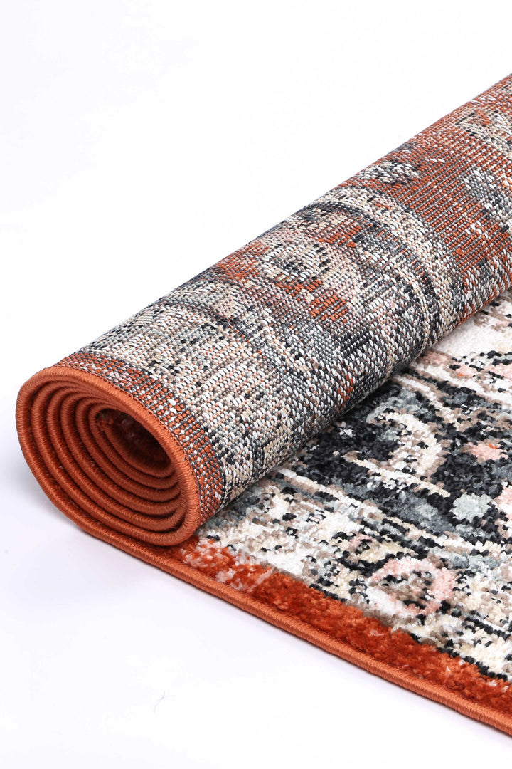 Rolled patterned area rug with orange and black tones, textured fabric detail