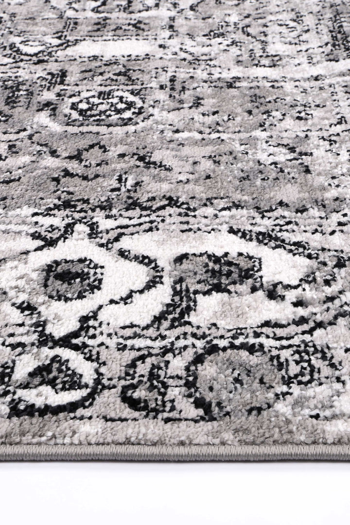 Close-up of a grey and white area rug with a floral pattern and textured pile