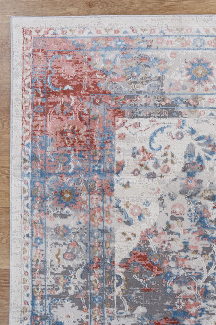 Colorful distressed area rug with red, blue, and gray floral patterns on hardwood floor
