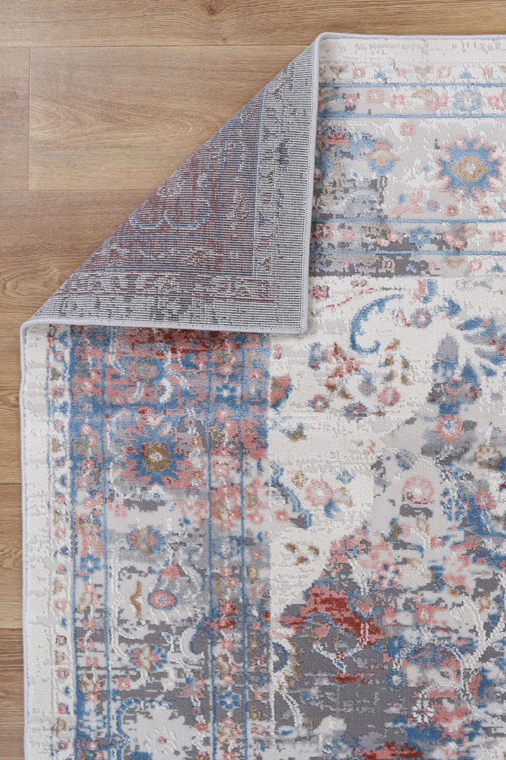 Corner of a multicolor floral area rug with blue, red, and beige patterns on wood floor