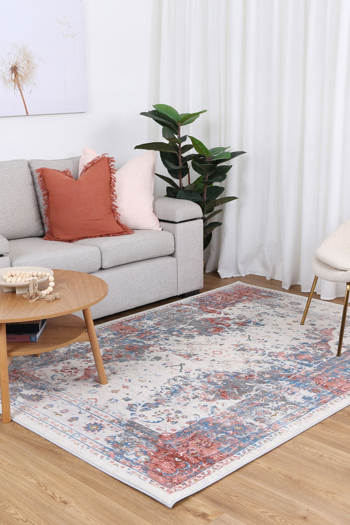 Living room with light gray sofa, colorful patterned area rug, coffee table, houseplant, and framed wall art