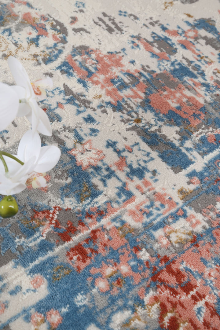 Abstract area rug with blue, red, and grey pattern, white orchid accent, home decor