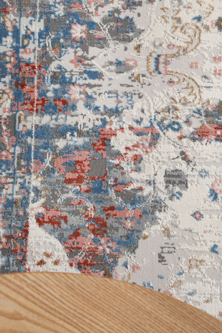 Abstract patterned area rug with blue, red, and beige colors under a light wood table