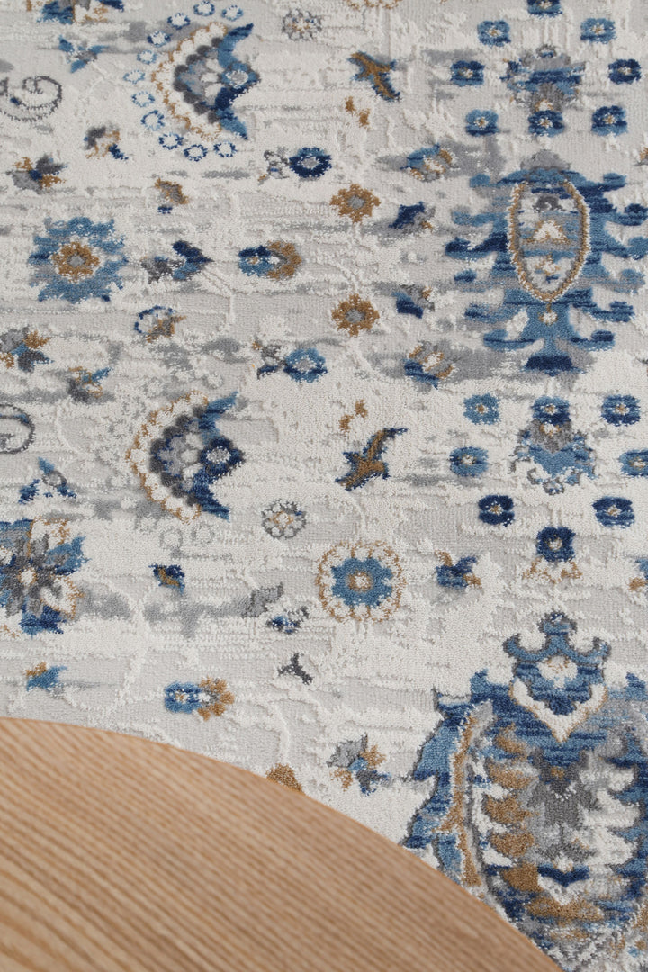 Blue and beige floral pattern area rug with part of a wooden table corner visible
