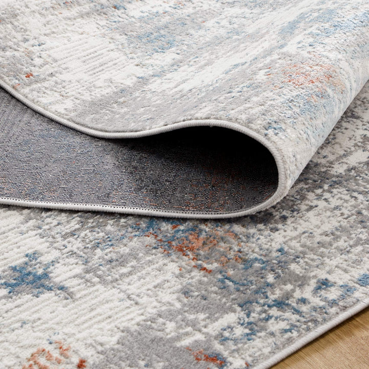 Modern area rug with abstract gray, blue, and orange pattern, close-up on texture