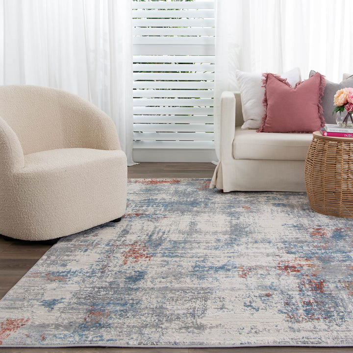Modern living room with abstract area rug, cream swivel chair, ivory sofa, and rattan coffee table