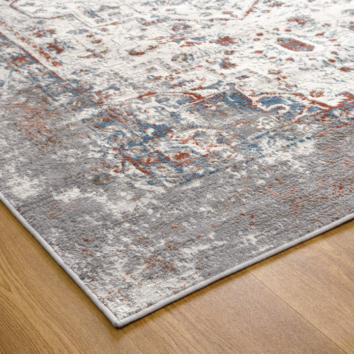 Modern area rug with distressed gray, blue, and rust pattern on hardwood floor