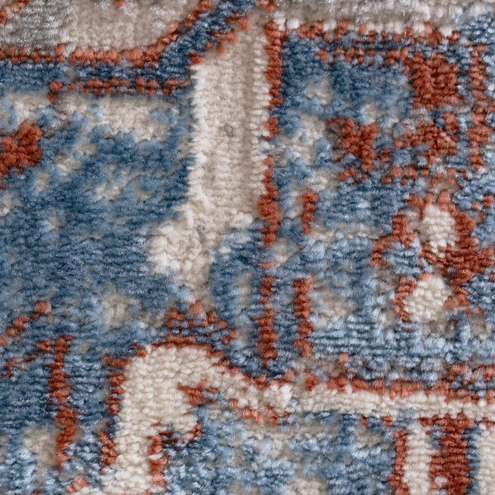 Close-up of patterned area rug fabric in blue, beige, and terracotta tones.