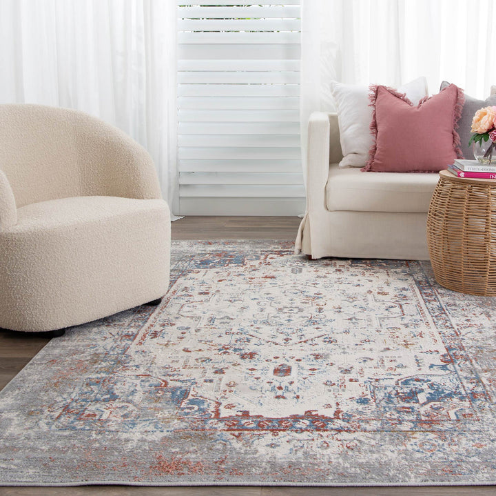 Modern living room with cream armchair, white sofa, pink accent pillow, and patterned area rug