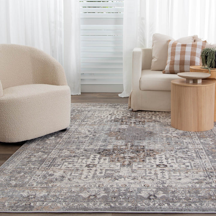 Modern living room with beige accent chair, cream sofa, patterned area rug, and round wooden tables