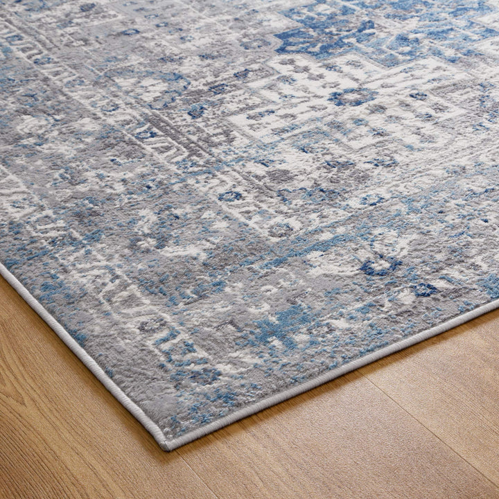 Corner of a modern area rug with blue and grey abstract pattern on wood floor