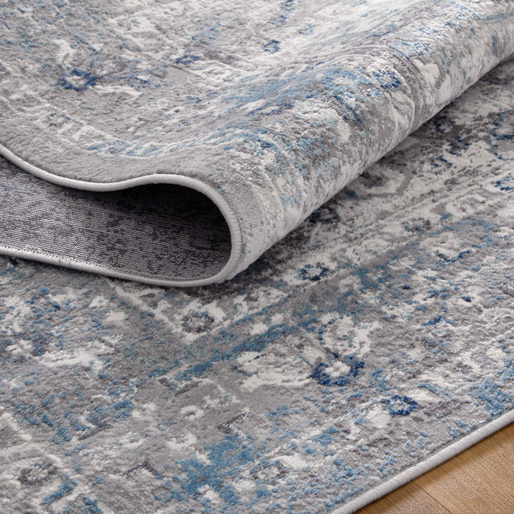 Gray and blue patterned area rug with soft texture shown partially folded on hardwood floor