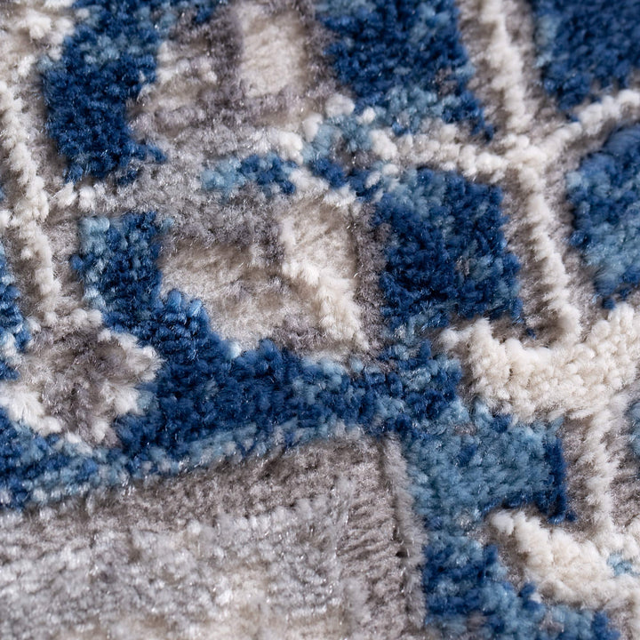 Close-up of plush blue, gray, and cream patterned area rug texture