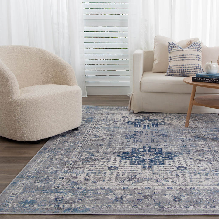 Modern living room with cream armchair, beige sofa, blue patterned area rug, and coffee table
