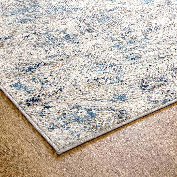 Modern area rug with blue and beige abstract pattern on light wood flooring